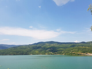 Fototapeta na wymiar The green color of the water of a wide lake. The hilly coast is overgrown with forest