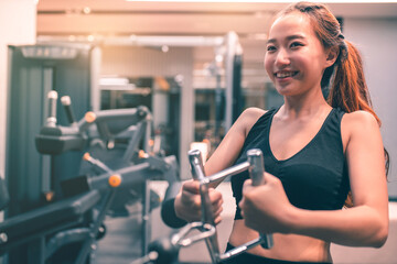 Fototapeta premium Muscular asian young woman with beautiful body doing exercises . Sporty girl lifting weights in gym.