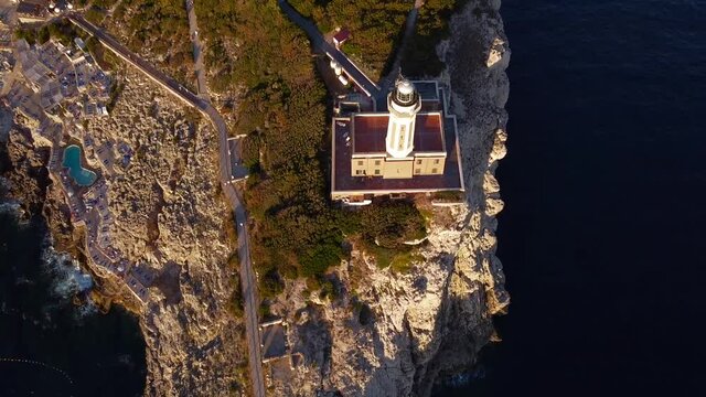 Aerial view (drone) at sunset of a lighthouse on the summit of a rocky. The Lighthouse of Punta Carena dominates the Southwestern coast of the island of Capri