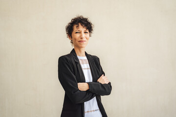 Portrait of smiling mature business woman standing arms crossed against wall