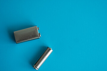 High voltage Volt 9V battery and alkaline AA battery on a blue background. Energy.