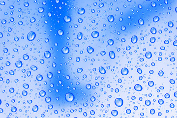Fototapeta na wymiar Large drops of rain and reflections of clouds on a blue background.