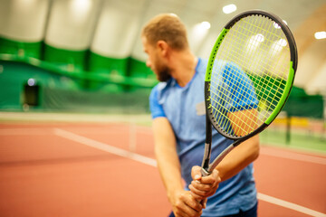 Instructor or coach teaching how to play tennis on a court indoor