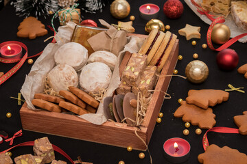 New Year and Christmas photo of box filled with homemade cakes on black background, with decorations and baking around.