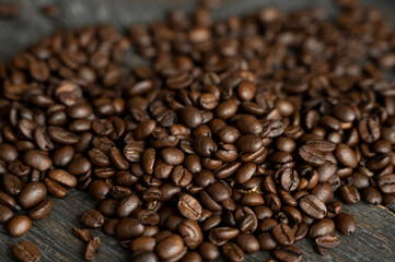 Naklejka premium Roasted arabica coffee beans scattered on a wooden table. Fresh coffee beans.