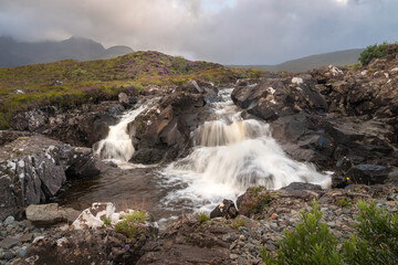Beautiful Sligachan waterfalls on the Isle of Skye in the Highlands of Scotland, the Cuillin mountains rising behind lit by sunset