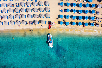 Aerial top down view to the umbrellas and the turquoise sea at the popular beach of Ornos, Mykonos island, Greece - obrazy, fototapety, plakaty