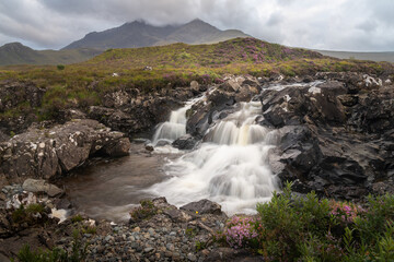 Beautiful Sligachan waterfalls on the Isle of Skye in the Highlands of Scotland, the Cuillin mountains rising behind lit by sunset