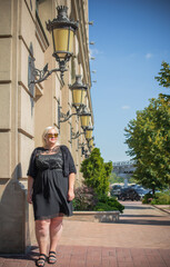 Plus size woman, American or European appearance walks in the city enjoying life. A young lady with excess weight, stylishly dressed in the center of the city. Natural beauty