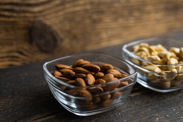 Almond, cachew and walnut in a small plates which standing on a black table. Nuts is a healthy vegetarian protein and nutritious food.