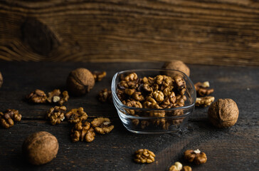 Walnut in a smale plate with scattered shelled nuts and whole nut which standing on a wooden vintage table. Walnuts is a healthy vegetarian protein nutritious food. Walnut on rustic old wood.