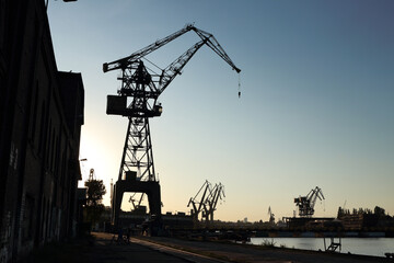Silhouette of  shipyard's tall crane. Industrial landscape - unused crane in formrer Gdansk Shipyard turned into sightseeing destination. Channels and other cranes in the background.