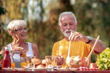 Senior couple drinking juice in nature.