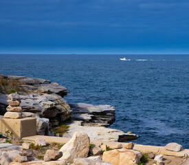 Rock cliffs over the ocean at Bronte Beach with views of the houses at Bondi Beach Sydney NSW Australia