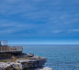 Rock cliffs over the ocean at Bronte Beach with views of the houses at Bondi Beach Sydney NSW Australia