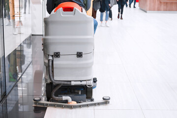 Worker cleaning supermarket floor on special washing and polishing machine in supermarket. Worker...