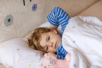 Cute little toddler girl wake up and sleep in bed with favourite soft plush toy lama. Upset sad baby child dreaming, healthy sleep of children by day.