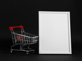 A frame and shopping cart on a black background, a blank for the design, concept. Copy space.