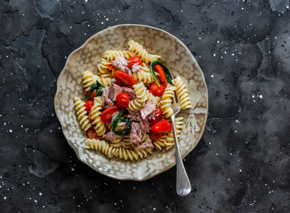 Sicilian pasta with canned tuna and cherry tomatoes on a dark background, top view