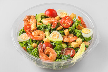 Healthy shrimp caesar salad in plastic package for take away or food delivery on white marble background. close up