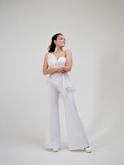 Fototapeta na wymiar A young brunette woman in a stylish and elegant pantsuit. Wedding suit with trousers, modern style.