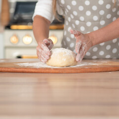 Knead dough, hand dough and flour close-up. A pastry chef in a grey polka-dot apron.