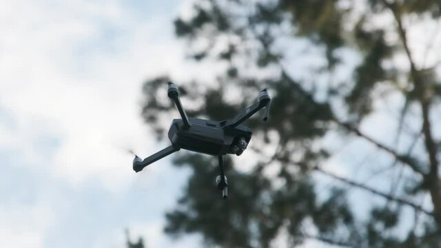Drone Hangs in the Air against the Blue Sky, View from Below. Slow Motion 240 fps