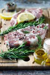Fresh raw meat with rosemary and spices on a wooden board. Pork steaks.