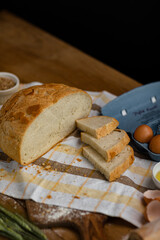 Fresh bread placed on a towel together with tomatoes and eggs. Bakery - gold rustic crusty loaves of bread.