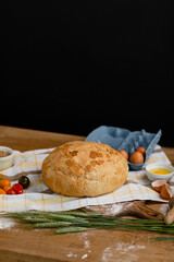 Fresh bread placed on a towel together with tomatoes and eggs. Bakery - gold rustic crusty loaves of bread.