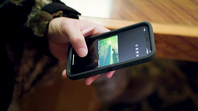 Man checking trail camera pictures on phone