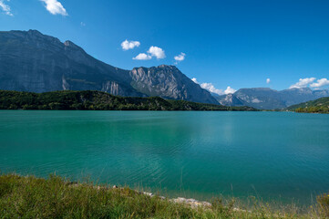 Cavedine Lake Trentino. Panorama of the turquoise blue water with mountains and vegetation on a summer day. Lago di Cavedine is a small alpine lake near, South Tyrol, Italy