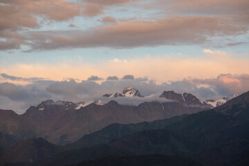 Sunset over the mountains, peaks covered with clouds, scenic sky 