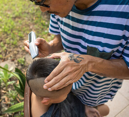 A man giving a boy a mohawk haircut in the garden during the community quarantine in the Philippines.