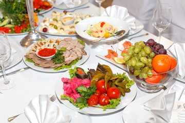 Cutting meat, pickles, fruit on a festive table