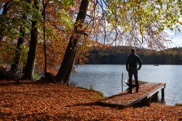 Mann geniesst die schöne Herbstlandschaft am See
