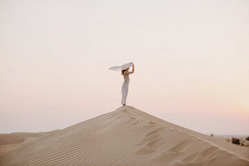 Fototapeta premium Woman holding scarf in the sand dune in desert