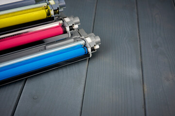 Yellow, cyan and magenta toner cartridges for replacement in a color printer on wooden background