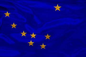 Photo of the national flag of Shatat Alaska USA on a luxurious texture of satin, silk with waves, folds and highlights, closeup, copy space