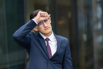 Portrait of tired man, exhausted overworked businessman in formal suit outdoors, he is suffering...