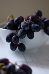 Black bunch of grapes in white bowl