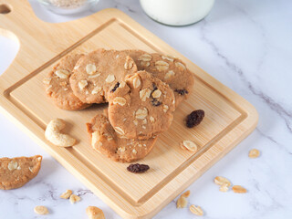 A pile of healthy homemade oat cookies put on a wooden plate over a marble table with copy space. .