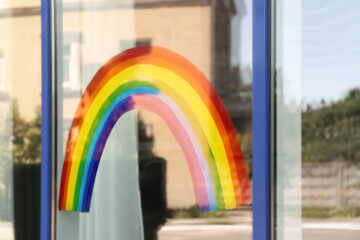 Painting of rainbow on window, view from outdoors. Stay at home concept