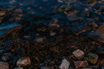 bright colored blue gold small pebbles in clear dark water sparkles in the sun, lake baikal