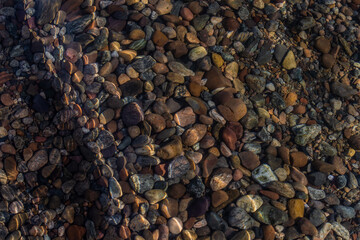 bright colored blue gold small pebbles in wave clear water sparkles in the sun, lake baikal