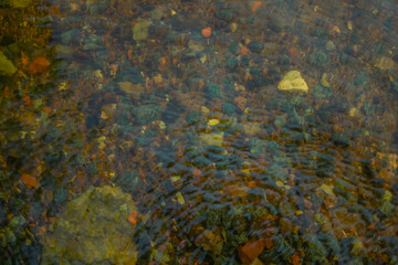 colored green blue gold small pebbles in clear water sparkles in the sun, lake baikal