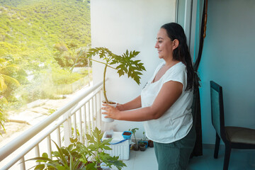 Woman with potted plants on a garden balcony. Floriculture is a hobby. Caucasian, mature mother growing ornamental plants