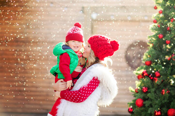 A blonde mother holds her laughing son under the snow