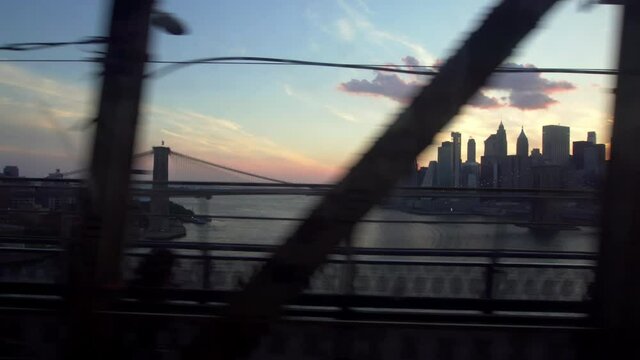 Crossing Manhattan Bridge on the Q train, sunset view over downtown New York and Brooklyn Bridge. Train Crossing.