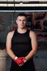 A man in red boxing bandages strikes. Male boxer during training